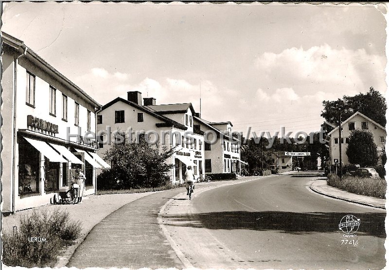 Lerum. Postganget 11 augusti 1959. Pressbyran 77414.jpg - Lerum.Postgånget 11 aug 1959.Förlag: Pressbyrån 77414.Bokhandeln och Heminredningen i första huset till vänster där SE-Banken ligger idag. Tredje huset finns fortfarande kvar med Lerums Delikatesssen och Salong VIP. Daterat "tisdagsförmiddag 1959!